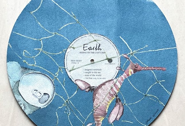 Eine künstlerisch gestaltete blaue Schallplatte mit einem Seepferdchen, das in einem Netz gefangen ist.